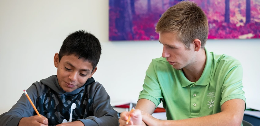 A student sitting with Compass Academy Network teacher